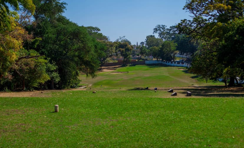Scenic view of a lush green golf course surrounded by tall trees on a sunny day in Blantyre, Malawi.