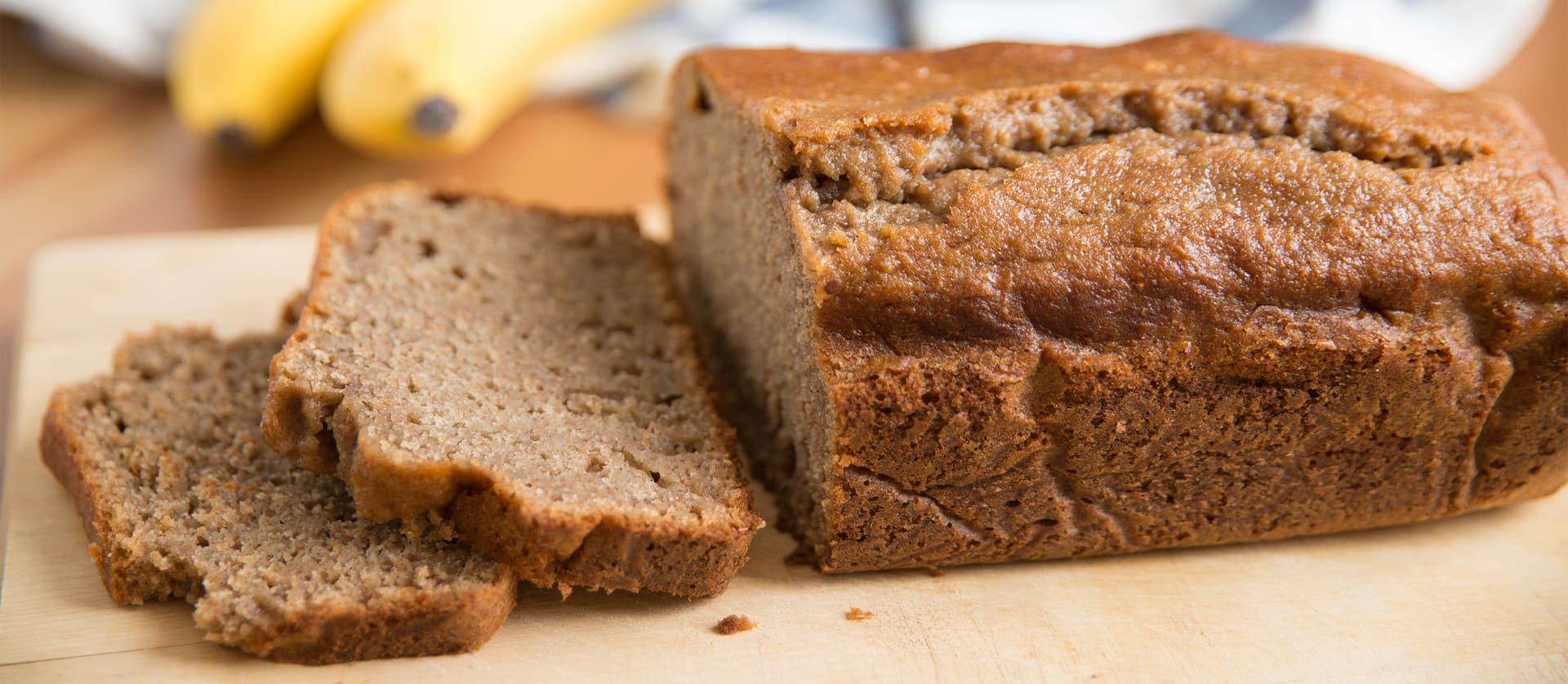 Close-up of freshly baked banana bread loaf sliced on a wooden board