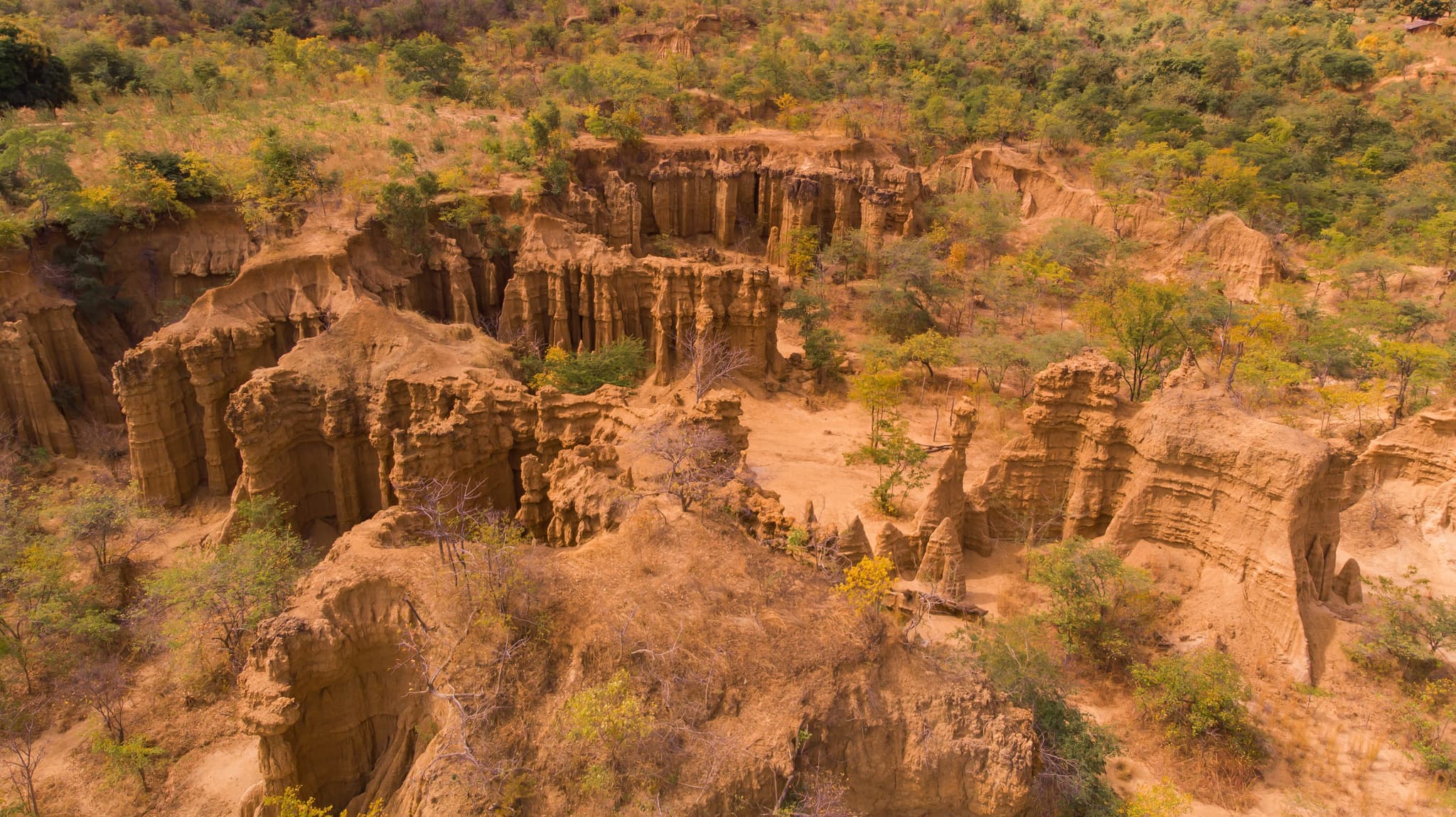 Aerial view of striking natural rock formations and rugged cliffs surrounded by green vegetation.